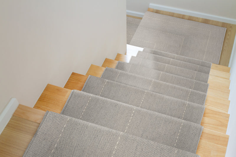 Gray stair runner rug on wooden stairs in a home interior